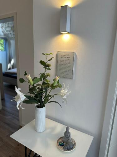 a vase of flowers on a table with a picture on the wall at Idylisches Ferienhaus in Edewecht