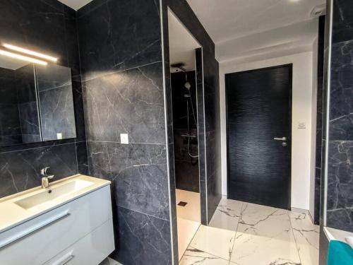 a black bathroom with a sink and a shower at Villa à 900m des plages in Locquirec