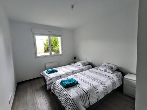 two beds in a room with white walls and a window at Villa à 900m des plages in Locquirec