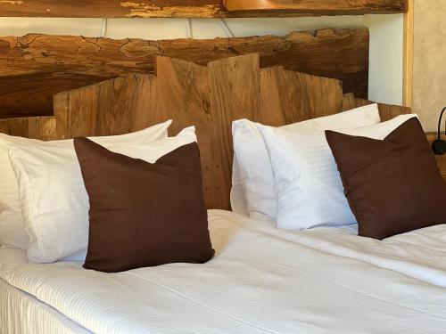 a large bed with white sheets and brown pillows at Hotel Nordmann,Racha in Ambrolauri