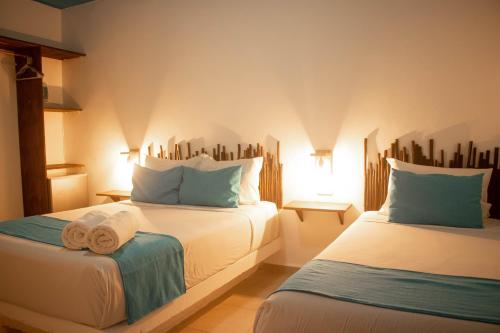 a hotel room with two beds with towels on them at Hotelito El Cuyo in El Cuyo