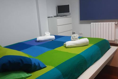 a large colorful bed with two pillows on it at Cantabria, amplio piso .Se admiten mascotas in Bádames