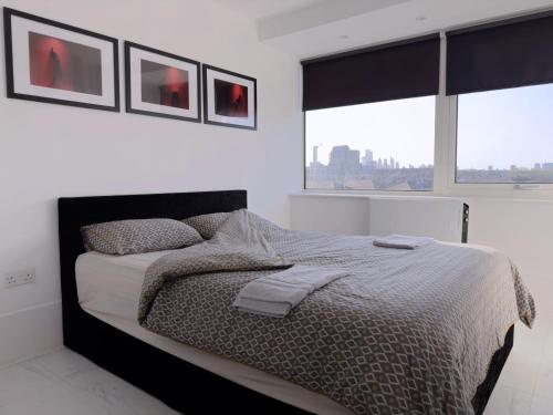 um quarto com uma cama grande e 2 janelas em Stylish & Cosy Nest near River Thames em Londres