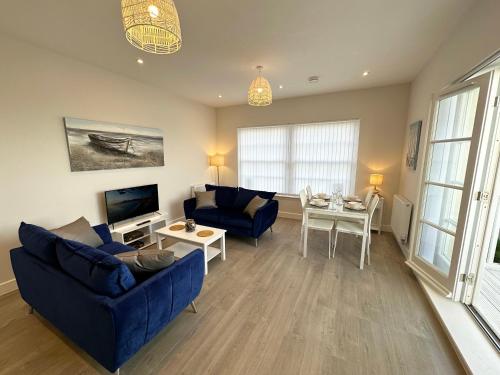 a living room with a blue couch and a table at Beachfront Bliss Apartment - Near Hythe - On Beach Seafront - Private Parking in Dymchurch