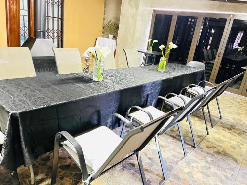 a long black table with chairs and vases of flowers at Duvha Guesthouse in Graskop