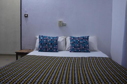 a bed with two blue pillows on top of it at Au cœur de Ouidah in Ouidah