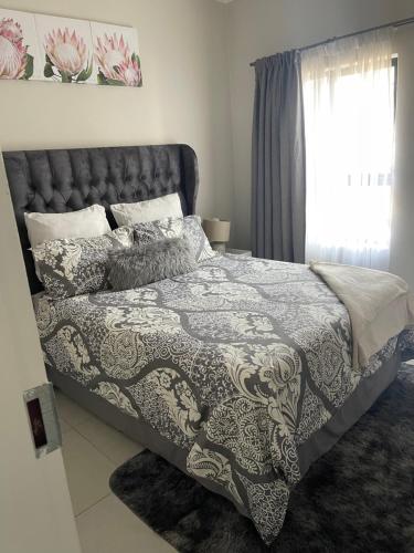 a bedroom with a bed and a window at Lovely Cozy Apartment in Midrand
