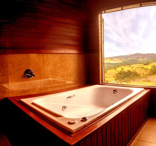 a large bath tub in a bathroom with a window at Vinícola D'alture - Cabana Casal - Sangiovese in São Joaquim