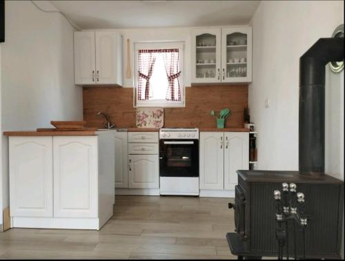 a kitchen with white cabinets and a black stove at Kuća za odmor Jeličić 