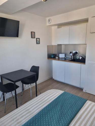 une petite cuisine avec une table et des chaises dans une pièce dans l'établissement MUTUM - Studios 2 personnes ou duplex 5 personnes , idéalement placés à 100m de la plage, à Dieppe