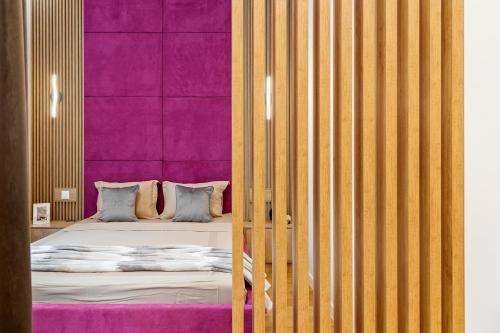 een slaapkamer met een bed met een paarse muur bij ONE Verdi Cozy Apartment in Boekarest