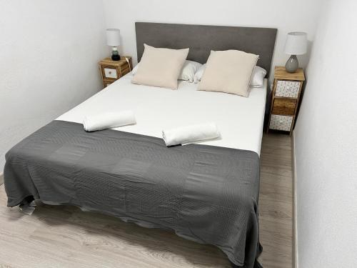 a bedroom with a large bed with white sheets and pillows at Apartamenticos La Paz I in Zaragoza