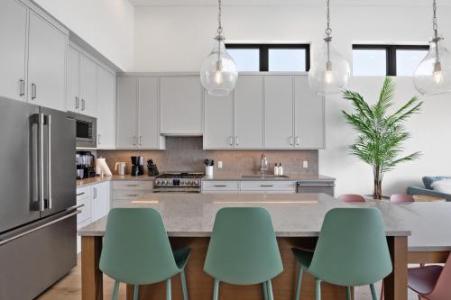 a kitchen with white cabinets and a table with green chairs at Beachfront Luxury Suite #18 at THE BEACH HOUSE in Campbell River