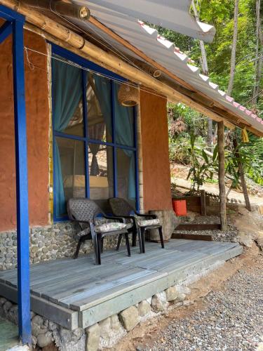 a porch of a house with two chairs on it at Ecolodge el Arca Bahia Solano in Bahía Solano