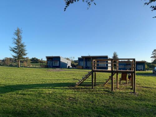a playground in a field with a house in the background at Cabaña Familiar de Descanso y Paseo - Puyehue in Puyehue