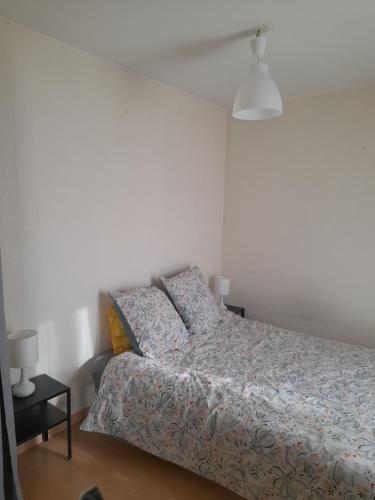 une chambre avec un lit et un mur blanc dans l'établissement Le fifty, à Bourges