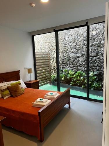 a bedroom with a bed and a large window at Arrenquinha Guesthouse 1 in São Vicente Ferreira