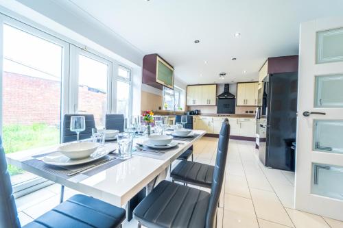 a kitchen with a table and chairs and a kitchen withwindows at Modern Spacious 4 Bed Hayes Home with Free Parking in Hayes