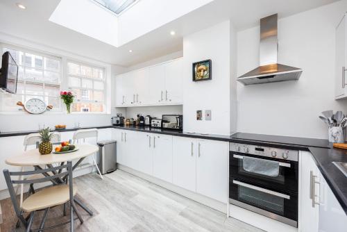 a kitchen with white cabinets and a small table at Quality Spitalfields Accommodations in London