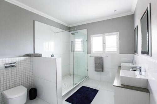 a bathroom with a shower and a toilet and a sink at Sunset Golf Villa in Langebaan