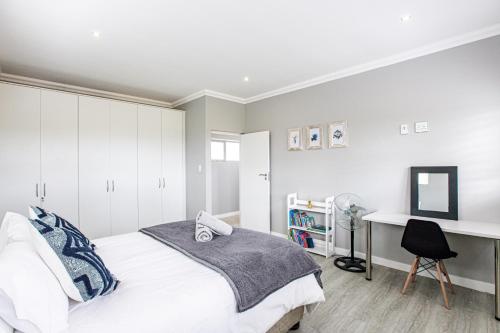 a bedroom with a white bed and a desk at Sunset Golf Villa in Langebaan