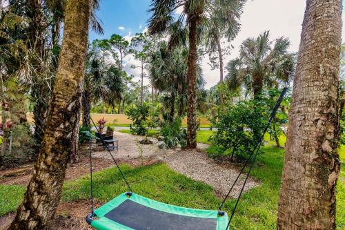 a swing in a yard between two palm trees at Beautiful Home in Naples with Huge Private Pool in Naples