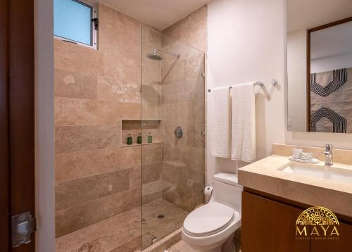 a bathroom with a shower and a toilet and a sink at NHOA 108A Lux 2BR Condo Plunge Pool in Aldea Zama in Tulum