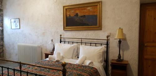 a bedroom with a bed with white pillows and a painting at Vilaeti Estia in Agios Konstantinos