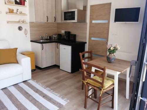 ein kleines Wohnzimmer mit einem Tisch und einer Küche in der Unterkunft Studio Les petites poules in Saint-Lyphard