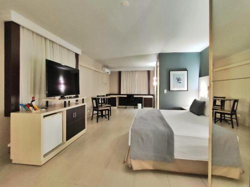 a hotel room with a bed and a flat screen tv at Hotel Metrópole Maringá in Maringá