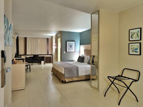 a hotel room with a bed and a kitchen at Hotel Metrópole Maringá in Maringá