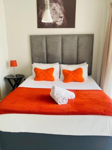 een slaapkamer met een bed met oranje en witte kussens bij The blyde-Luxury one bedroom apartment in Pretoria