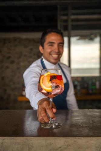 a man holding a drink with an orange in it at Jama Campay - Homes Resort & Spa in Jama