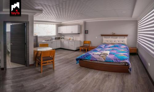 a bedroom with a bed and a table and a kitchen at TEYFA Hospedaje - Edificio in Atuntaqui