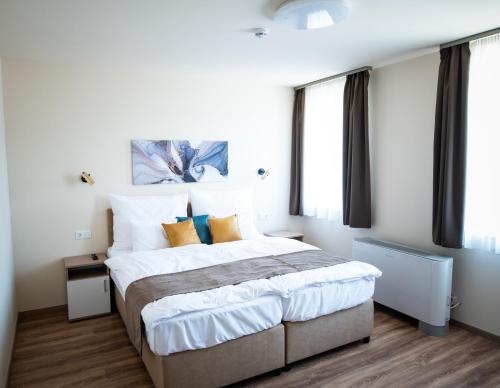 um quarto com uma cama grande e janelas em Elixír Panzió em Nyírbátor