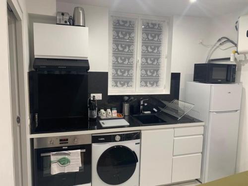 une petite cuisine avec une cuisinière et un micro-ondes dans l'établissement Logement proche Paris Stade de France CDG airport-idéal J-O, à Aubervilliers