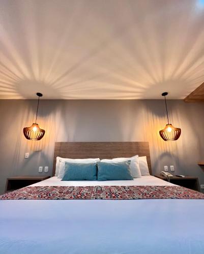 a bedroom with a large white bed with two lights at Hotel Buena Vista Express in Bucaramanga