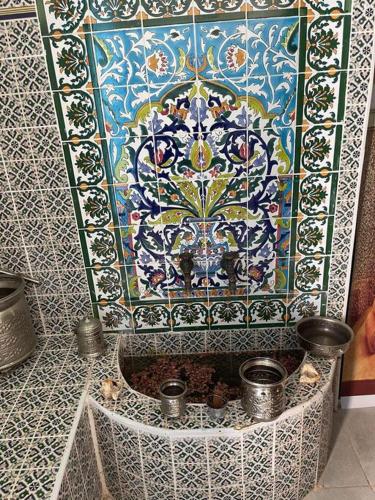 a colorful tile wall with a fountain in a room at Dar Lella Hasna in Sfax