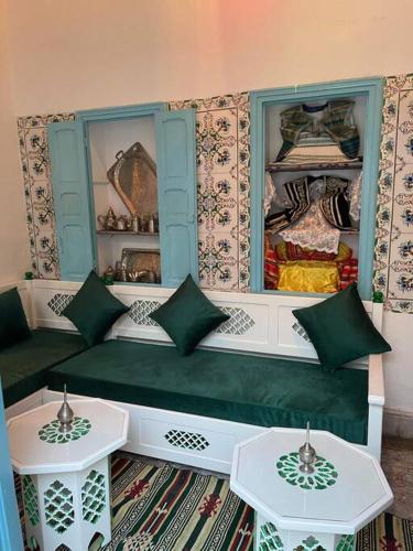 una habitación con un banco verde y dos mesas en Dar Lella Hasna, en Sfax