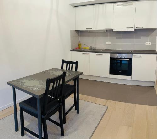 cocina con mesa, 2 sillas y microondas en Élégant appartement (quartier européen), en Bruselas