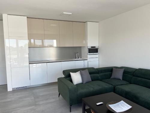 a living room with a green couch and a kitchen at Pri jazere - Golf rezort in Hrubá Borša