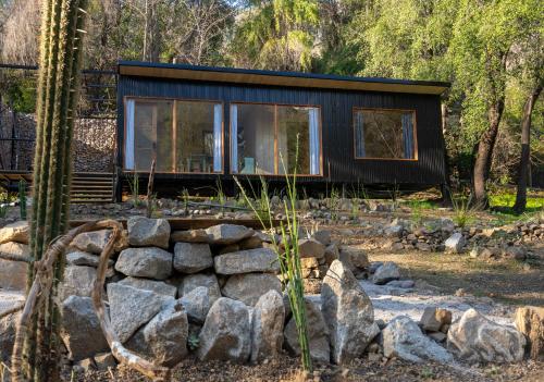 ein schwarzes winziges Haus im Wald mit Felsen in der Unterkunft Casa clara San Alfonso in San Alfonso