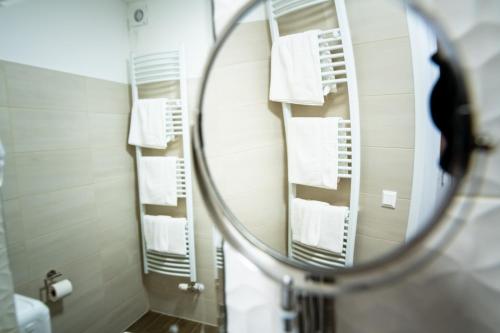 uma casa de banho com um espelho e toalhas brancas em Elixír Panzió em Nyírbátor
