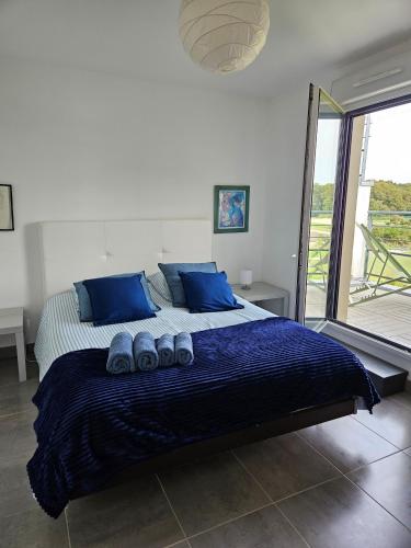 - une chambre dotée d'un grand lit avec des oreillers et des chaussures bleus dans l'établissement VIKI - THALASSO CONCARNEAU - 2 à 4 personnes, à Concarneau