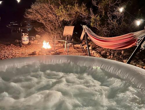 a bath tub filled with snow next to a hammock and a fire at The Juniper Ranch and Retreat in Canyon Lake