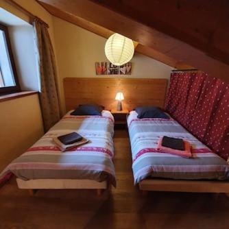 a bedroom with two beds and a chandelier at L´ouillon in Lanslebourg-Mont-Cenis