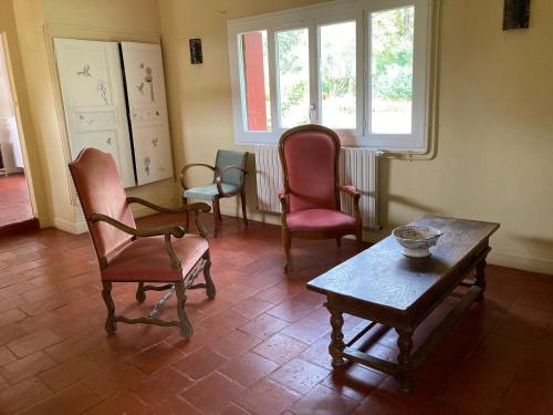 a living room with chairs and a table and a window at Métairie de Moutiques in Cazaubon