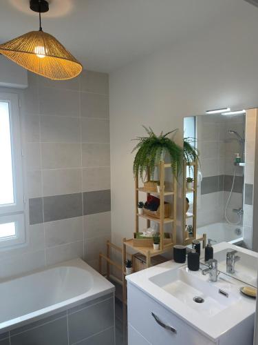 une salle de bain avec un lavabo, une baignoire et un miroir dans l'établissement Villa des Cerisiers, à Saint-Nazaire