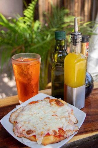 a pizza on a plate on a table with a drink at Hotelito El Cuyo in El Cuyo
