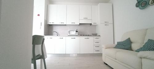 a kitchen with white cabinets and a couch in a room at A Domo Tua in Alghero